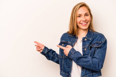 Beyaz arka planda izole edilmiş beyaz tenli genç bir kadın işaret parmağıyla işaret ederek heyecanlanıyor..