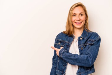 Beyaz arka planda izole edilmiş genç beyaz bir kadın gülümsüyor ve boş alanda bir şeyler gösteriyor..