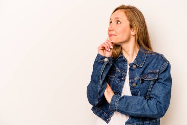 Beyaz arka planda izole edilmiş genç beyaz kadın rahatlamış bir şeyin fotokopi odasına baktığını düşünüyor..