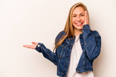 Beyaz arka planda izole edilmiş genç beyaz kadın avuç içinde fotokopi alanı tutuyor, el üstünde tutuyor. Şaşırmış ve mutlu..