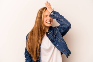 Beyaz arka planda izole edilmiş genç beyaz bir kadın bir şeyi unutuyor. Alnına avuç içi ve gözlerini kapayarak vuruyor..