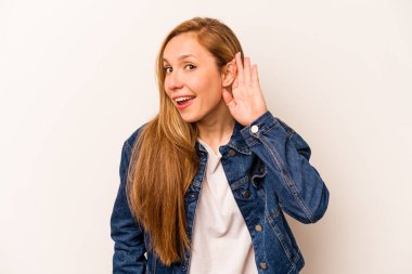 Beyaz arka planda izole edilmiş genç beyaz kadın bir dedikoduyu dinlemeye çalışıyor..