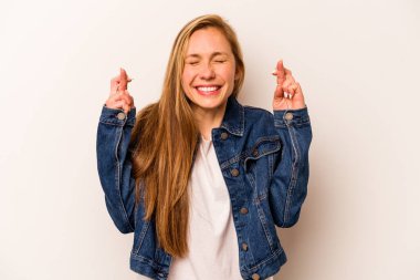 Beyaz arka planda izole genç beyaz kadın şans dilemek için parmaklarını çapraz