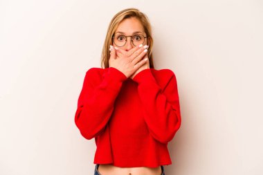 Beyaz arka planda izole edilmiş genç beyaz kadın elleriyle ağzını kapatırken şok oldu..