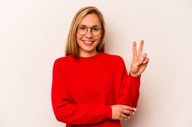 Beyaz arka planda izole edilmiş genç beyaz kadın iki numarayı parmaklarıyla gösteriyor..