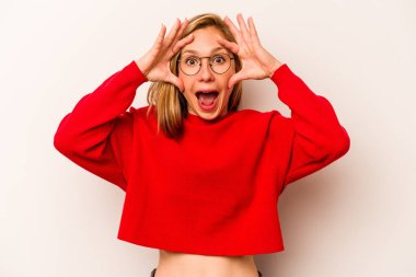 Beyaz arka planda izole genç beyaz kadın bir başarı fırsatı bulmak için gözlerini açık tutuyor..