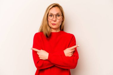 Beyaz arka plan noktalarında izole genç beyaz kadın, iki seçenek arasında seçim yapmaya çalışıyor.