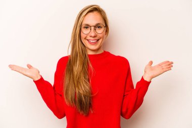 Beyaz arka planda izole genç beyaz kadın kollarıyla ölçek yapar, mutlu ve kendinden emin hisseder..