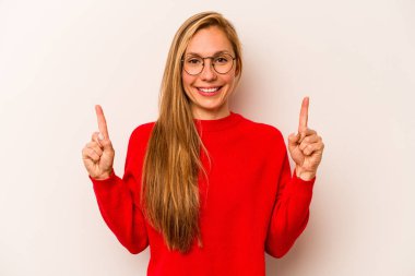 Beyaz arka planda izole edilmiş genç beyaz kadın iki parmağı da boş bir alan gösteriyor..