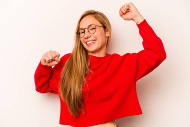 Beyaz arka planda izole edilmiş genç beyaz bir kadın özel bir günü kutluyor, atlıyor ve enerjiyle kollarını kaldırıyor..