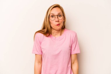 Beyaz arka planda izole edilmiş genç beyaz kadın omuzlarını silker ve gözleri açık kalır..