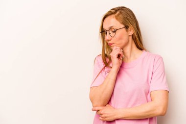 Beyaz arka planda soyutlanmış beyaz tenli genç bir kadın şüpheli ve şüpheci bir ifadeyle yana bakıyor..