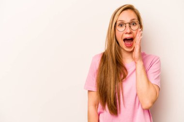 Beyaz arka planda izole genç beyaz kadın yüksek sesle bağırıyor, gözleri açık ve elleri gergin tutuyor..