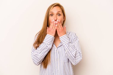 Beyaz arka planda izole edilmiş genç beyaz kadın elleriyle ağzını kapatırken şok oldu..