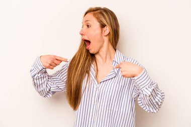 Beyaz arka planda izole edilmiş genç beyaz bir kadın parmağını göstererek şaşırdı, geniş bir gülümsemeyle..