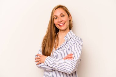 Beyaz arka planda kendini güvende hisseden, kararlılıkla kollarını kavuşturan beyaz tenli genç bir kadın..