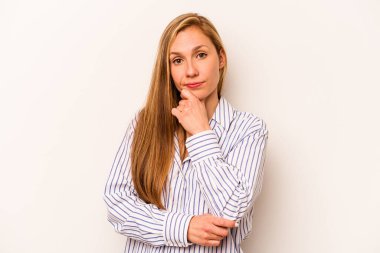 Beyaz arka planda izole edilmiş genç beyaz kadın şüpheli, belirsiz, seni muayene ediyor..