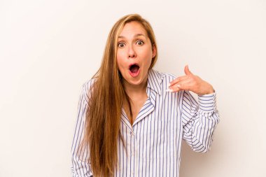 Beyaz arka planda izole edilmiş genç beyaz bir kadın bir şeye gülüyor, elleriyle ağzını kapatıyor..