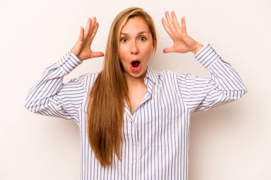 Beyaz arka planda izole genç beyaz kadın zaferi ya da başarıyı kutluyor, şaşırıyor ve şok oluyor..