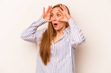 Beyaz arka planda izole genç beyaz kadın bir başarı fırsatı bulmak için gözlerini açık tutuyor..