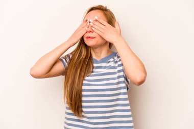 Beyaz arka planda izole edilmiş genç beyaz kadın elleriyle gözlerini kapatmaktan korkuyor..