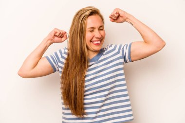 Beyaz arka planda izole edilmiş genç beyaz bir kadın özel bir günü kutluyor, atlıyor ve enerjiyle kollarını kaldırıyor..