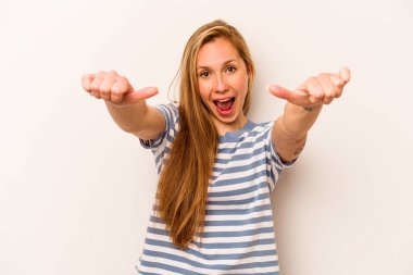 Beyaz arka planda soyutlanmış beyaz tenli genç bir kadın iki parmağını da kaldırıyor, gülümsüyor ve kendinden emin..