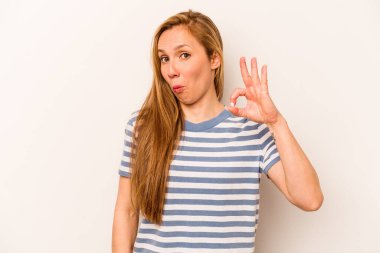 Beyaz arka planda izole edilmiş genç beyaz kadın bir göz kırptı ve elleriyle iyi bir jest yaptı..