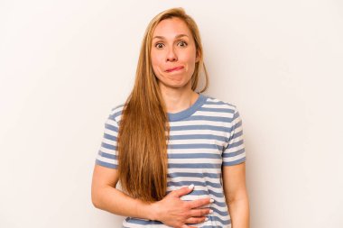 Beyaz arka planda izole genç beyaz kadın karnına dokunuyor, nazikçe gülümsüyor, yemek yiyor ve tatmin oluyor..