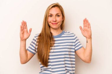 Beyaz arka planda izole edilmiş genç beyaz bir kadın. Elinde parmakları olan, gülümseyen ve kendinden emin bir şey tutuyor..