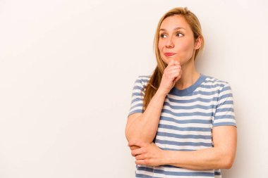 Beyaz arka planda soyutlanmış beyaz tenli genç bir kadın şüpheli ve şüpheci bir ifadeyle yana bakıyor..