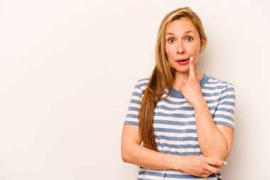 Beyaz arka planda soyutlanmış beyaz tenli genç bir kadın şüpheli ve şüpheci bir ifadeyle yana bakıyor..