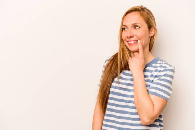 Beyaz arka planda izole edilmiş genç beyaz kadın rahatlamış bir şeyin fotokopi odasına baktığını düşünüyor..