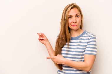 Beyaz arka planda izole edilmiş genç beyaz kadın işaret parmağıyla fotokopi alanını işaret ederek şok oldu..