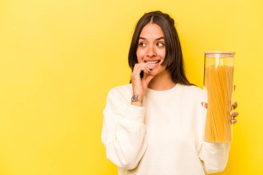 Sarı arka planda izole edilmiş spagetti kavanozunu tutan genç İspanyol kadın bir şeyin fotokopi odasına baktığını düşünerek rahatladı..