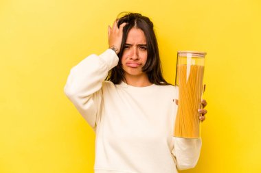 Sarı arka planda izole edilmiş spagetti kavanozunu tutan genç İspanyol kadın şok geçiriyordu. Önemli bir toplantıyı hatırladı..