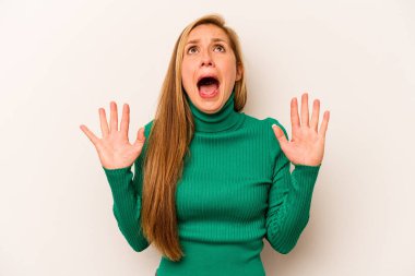 Beyaz arka planda izole edilmiş genç beyaz kadın gökyüzüne haykırıyor, yukarı bakıyor, hayal kırıklığına uğramış..