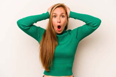Beyaz arka planda izole edilmiş genç beyaz kadın şaşırmış ve şok olmuş..