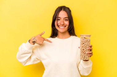 Elinde nohut kavanozu tutan genç İspanyol kadın. Sarı arka plandaki izole edilmiş, gömlek fotokopi alanını işaret ediyor. Gururlu ve kendinden emin.