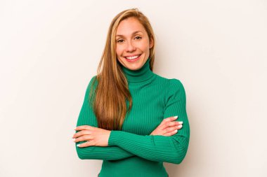 Beyaz arka planda kendini güvende hisseden, kararlılıkla kollarını kavuşturan beyaz tenli genç bir kadın..