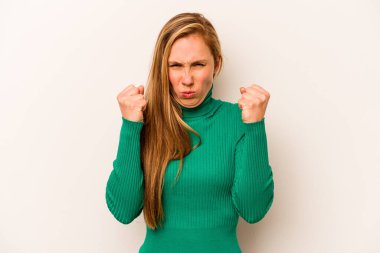 Beyaz arka planda izole edilmiş genç beyaz kadın yumruğunu kameraya gösteriyor, agresif yüz ifadesi var..