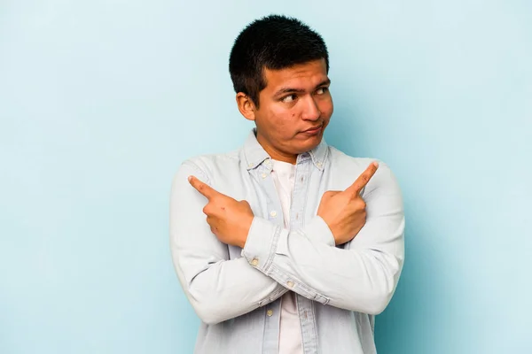 Young Hispanic Man Isolated Blue Background Points Sideways Trying Choose — стоковое фото