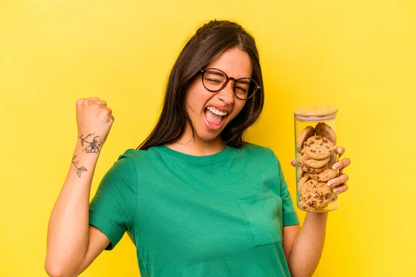 Jonge Spaanse Vrouw Met Een Koekjestrommel Geïsoleerd Gele Achtergrond Hef — Stockfoto