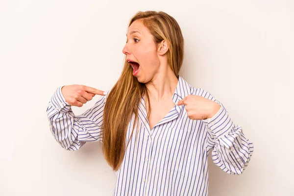 Beyaz arka planda izole edilmiş genç beyaz bir kadın parmağını göstererek şaşırdı, geniş bir gülümsemeyle..