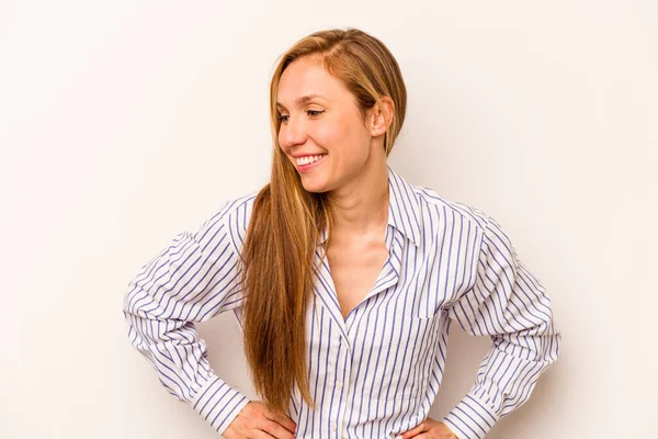 Beyaz arka planda izole genç beyaz kadın mutlu bir şekilde gülüyor ve ellerini karnının üstünde tutarak eğleniyor..