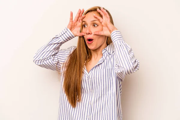 Beyaz arka planda izole genç beyaz kadın bir başarı fırsatı bulmak için gözlerini açık tutuyor..