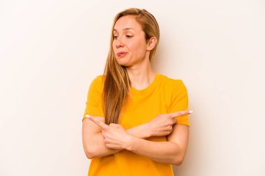 Beyaz arka plan noktalarında izole genç beyaz kadın, iki seçenek arasında seçim yapmaya çalışıyor.