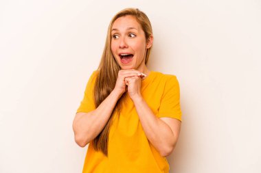 Beyaz arka planda izole edilmiş genç beyaz bir kadın şans için dua ediyor, şaşırmış ve ağzını açıp önüne bakıyor..