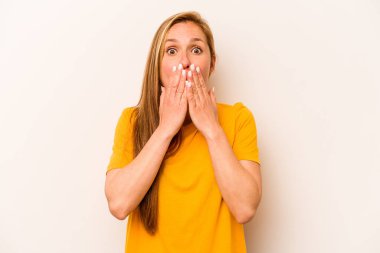 Beyaz arka planda izole edilmiş genç beyaz kadın şok olmuş, elleri ağızda, yeni bir şey keşfetmeye hevesli..