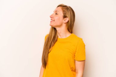 Beyaz arka planda izole edilmiş genç beyaz kadın rahat ve mutlu bir şekilde gülüyor, boynunda dişlerini gösteriyor..